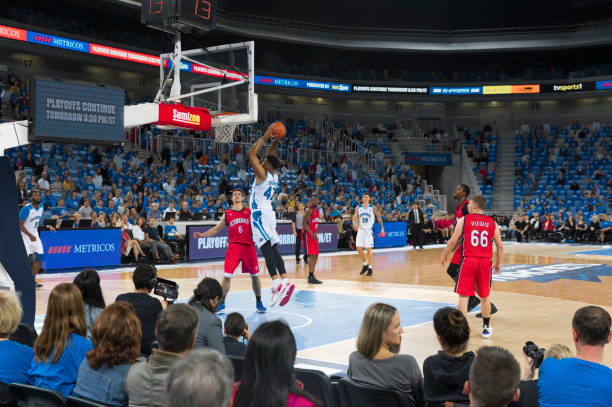 Basketball player in white jersey jumping to score slam dunk during match.