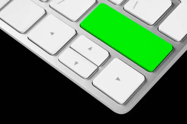 Photo of Close up view of a computer notebook keyboard with one green empty button isolated on blacke background. Technology background empty space for text