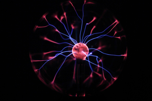 High-voltage arc at coil of Tesla. Plasma lamp. Abstract concept of electric power. The electric lightning bolts coming from the center of the glass sphere.