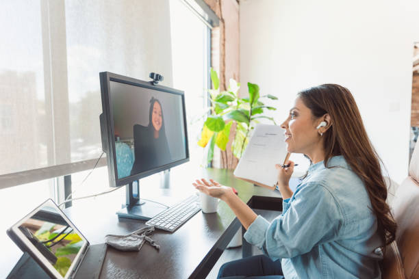 Elementary student talks with teacher during virtual tutoring session During an online tutoring session, a mid adult female elementary school teacher gestures while talking with a female student. stay at home saying stock pictures, royalty-free photos & images