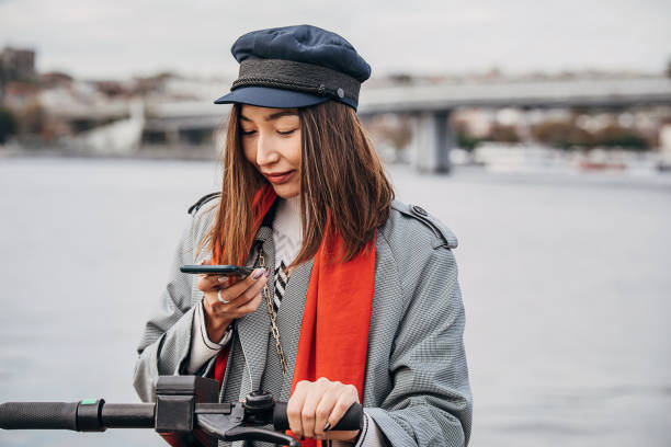 istock Modern Asian woman on electric scooter using phone 1289434668