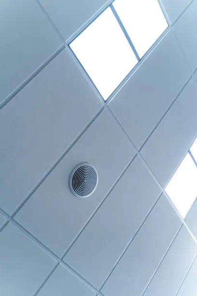 Fluorescent lamps on the modern ceiling. Luminous ceiling of square tiles.