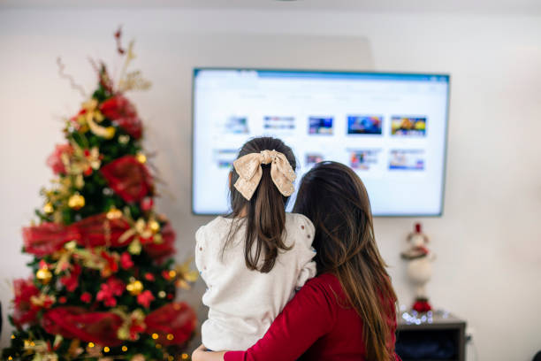 Mom and daughter watching tv in Christmas stock photo