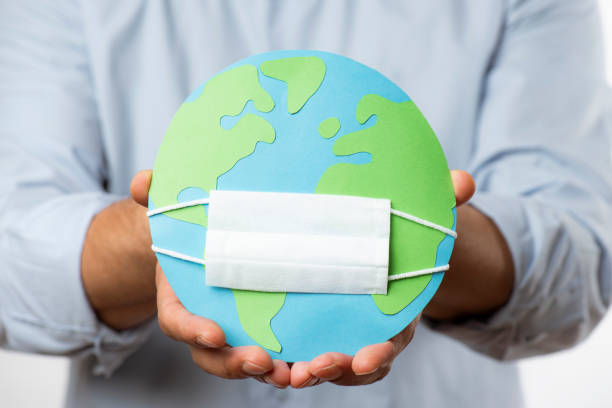 istock Hand Holding Globe And a Face Mask 1289437981