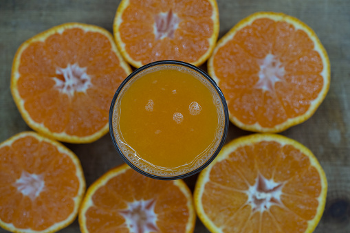 Delicious fresh squeezed tangerine juice in a transparent glass. Peeled sliced mandarin orange close up pieces.