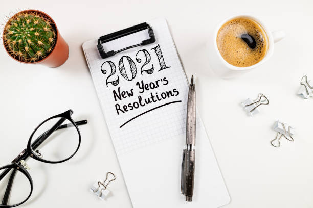istock New year resolutions 2021 on desk. 2021 goals list with notebook, coffee cup and eyeglasses on white desk. Goals, plan, strategy, resolutions, business, idea 1289440730