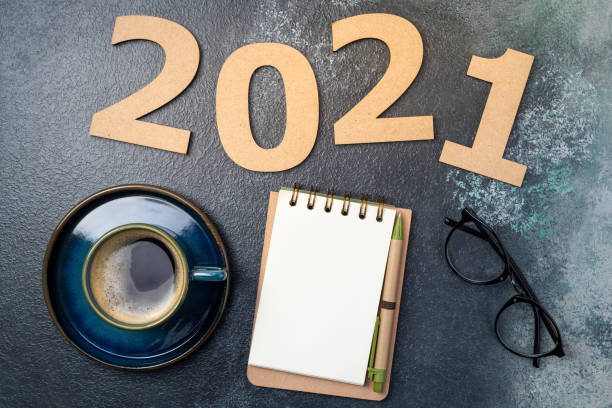 istock New year 2021 and notebook on desk. 2021 template with open notebook, coffee cup, eyeglasses on blue background. Goals, plan, strategy, resolutions, idea concept 1289440869