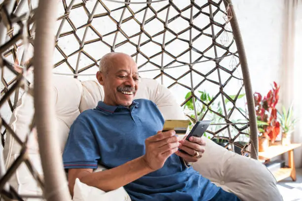 adult senior man using mobile phone and holding credit card in hand