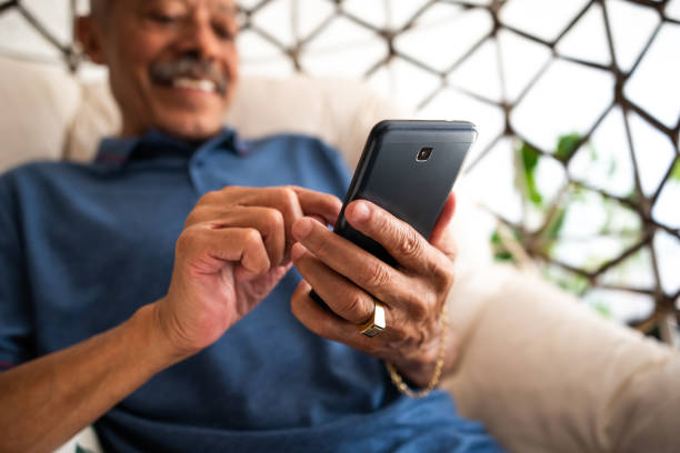 Adult senior man using mobile phone at home Adult senior man using mobile phone at home one senior man only stock pictures, royalty-free photos & images