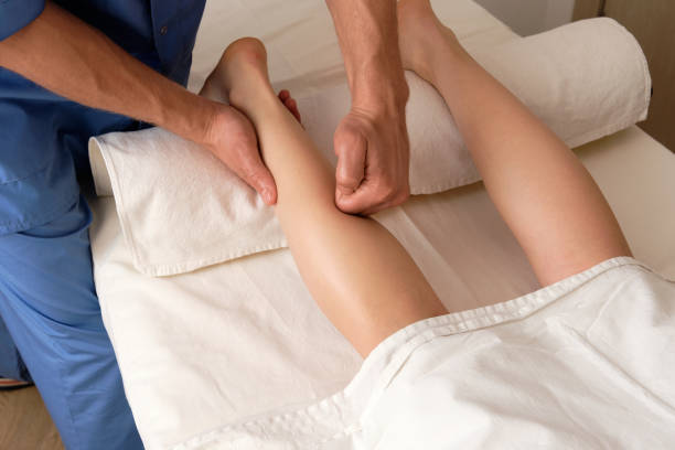istock masseur dressed in uniform makes legs massage to his client in spa parlor. 1289444088