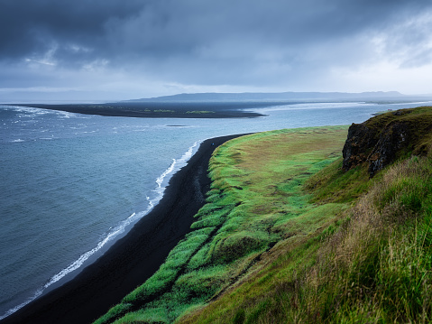 Seashore in Iceland. High rocks and grass at the day time near sea. Natural landscape at the summer. Icelandic travel image