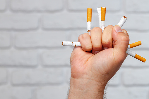 Male hand breaking cigarettes close up quitting bad habit