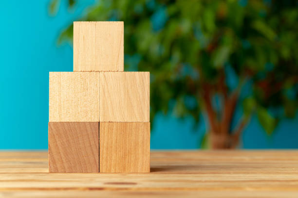 istock Wooden blocks on desk against blurred plant background 1289456761