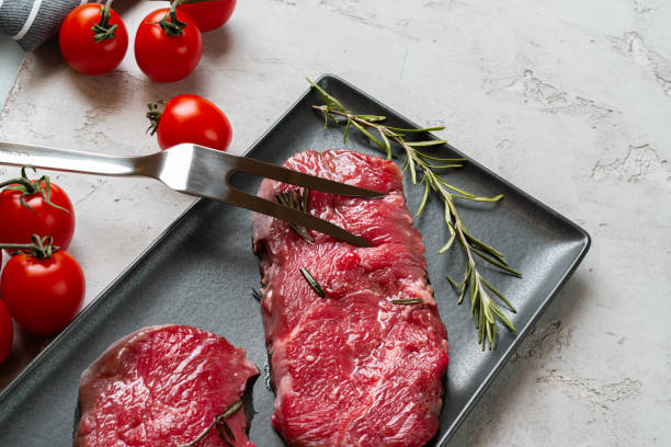 два свежих сырых мясных стейка на черной керамической тарелке - meat raw beef love стоковые фото и изображения