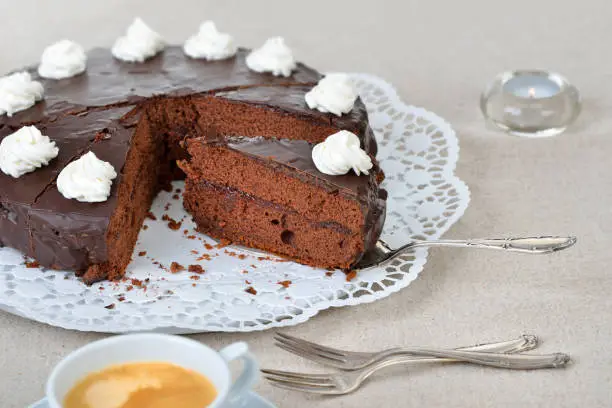 Delicious Viennese cocoa cake with red currant jam and covered with fine dark chocolate and cream,  served with coffee