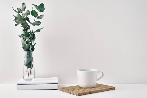 istock A mug, a stack of books, a wooden board and a transparent vase with eucalyptus branches. Eco-friendly materials in interior decor, minimalism. Copy space, mock up. 1289468021