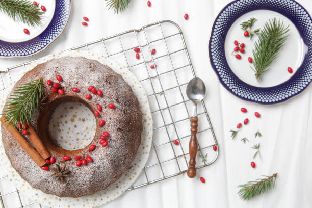 istock Festive bundt cake decorated with red berries and fir branches on white background. 1289473401