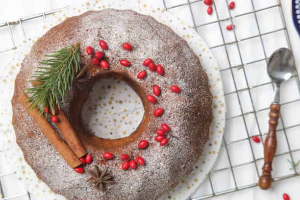 istock Festive bundt cake decorated with red berries and fir branches on white background. 1289473652