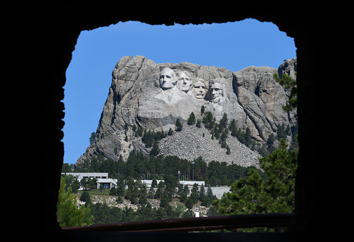 You need a luck - or careful planning - to catch a rarely seen glimpse of the Mount Rushmore through a tunnel. Mt Rushmore National Monument sculpture in South Dakota viewed across the Doane Robinson Tunnel on route 16A (Iron Mountain Road) , which - by the way - is a historical landmark,