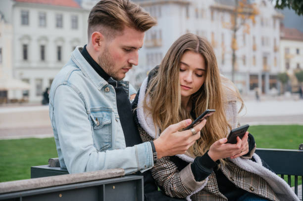 istock Young couple sitting using their smart phones 1289478984