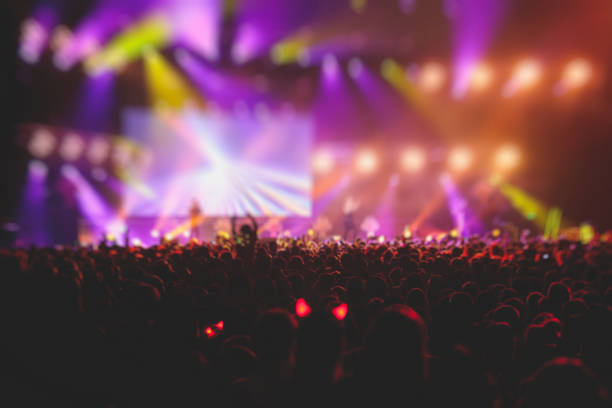 istock A crowded concert hall with scene stage lights, rock show performance, with people silhouette, colourful confetti explosion fired on dance floor air during a concert festival 1289480366
