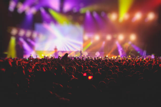 istock A crowded concert hall with scene stage lights, rock show performance, with people silhouette, colourful confetti explosion fired on dance floor air during a concert festival 1289480368