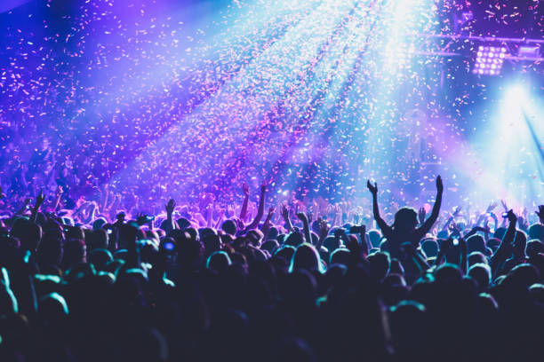 istock A crowded concert hall with scene stage lights, rock show performance, with people silhouette, colourful confetti explosion fired on dance floor air during a concert festival 1289480402