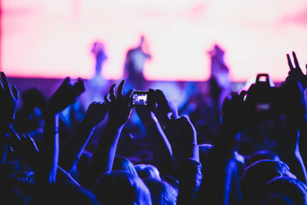istock A crowded concert hall with scene stage lights, rock show performance, with people silhouette, colourful confetti explosion fired on dance floor air during a concert festival 1289480427
