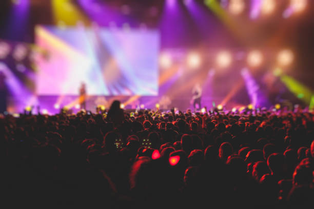 istock A crowded concert hall with scene stage lights, rock show performance, with people silhouette, colourful confetti explosion fired on dance floor air during a concert festival 1289480437