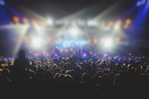 istock A crowded concert hall with scene stage lights, rock show performance, with people silhouette, colourful confetti explosion fired on dance floor air during a concert festival 1289481071