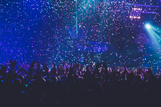 istock A crowded concert hall with scene stage lights, rock show performance, with people silhouette, colourful confetti explosion fired on dance floor air during a concert festival 1289481086