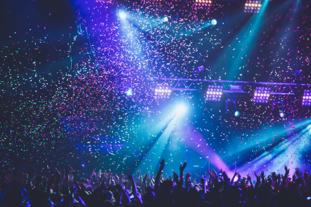 istock A crowded concert hall with scene stage lights, rock show performance, with people silhouette, colourful confetti explosion fired on dance floor air during a concert festival 1289481167
