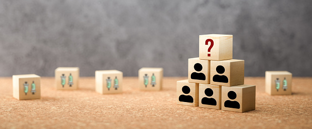 cubes with a syringe symbol and stacked cubes with person symbols symbolizing allocation problem of vaccination on cork and concrete background - 3d illustration