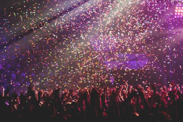 istock A crowded concert hall with scene stage lights, rock show performance, with people silhouette, colourful confetti explosion fired on dance floor air during a concert festival 1289481346