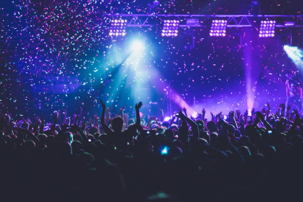 istock A crowded concert hall with scene stage lights, rock show performance, with people silhouette, colourful confetti explosion fired on dance floor air during a concert festival 1289481397