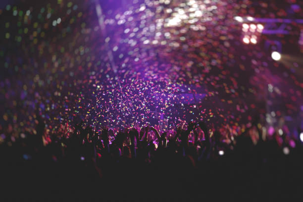 istock A crowded concert hall with scene stage lights, rock show performance, with people silhouette, colourful confetti explosion fired on dance floor air during a concert festival 1289481446