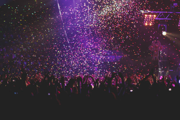 istock A crowded concert hall with scene stage lights, rock show performance, with people silhouette, colourful confetti explosion fired on dance floor air during a concert festival 1289481456