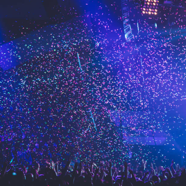 istock A crowded concert hall with scene stage lights, rock show performance, with people silhouette, colourful confetti explosion fired on dance floor air during a concert festival 1289481521