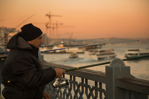 İstanbul-Turkey, 01.02.2019: man is fishing on the Galata Bridge at sunset. Fishing in Turkey,