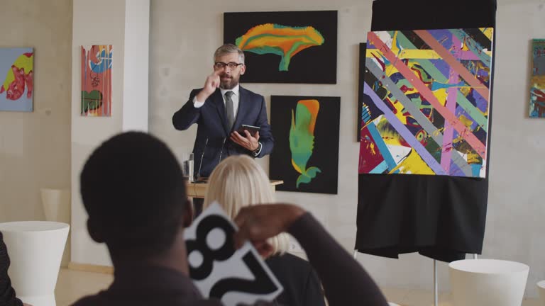 Male Auctioneer Conducting Auction in Art Gallery