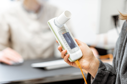 Patient holding spirometer, medical instrument for measuring breathing movemnts, close-up