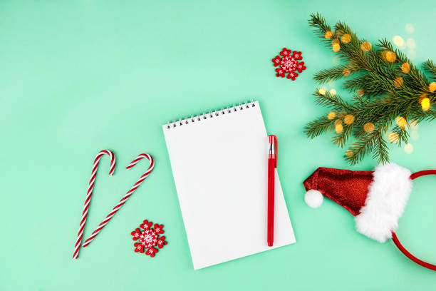 istock Christmas composition, wish list concept. Notebook with pen, spruce branches, decoration and Santa Claus with red hat and beard 1289504047