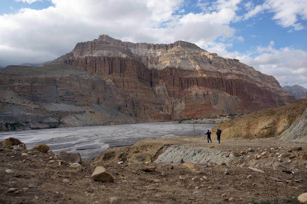 турист и швейцар идут по берегам реки кали гандаки на фоне гималайских гор. - lo стоковые фото и изображения