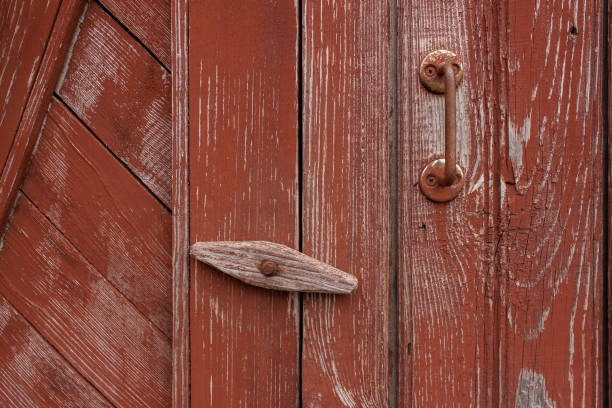 a porta do antigo banheiro da vila está fechada com um parafuso de balanço. um obturador giratório para uma porta de madeira vermelha com tinta arranhada. - peeling paint audio - fotografias e filmes do acervo