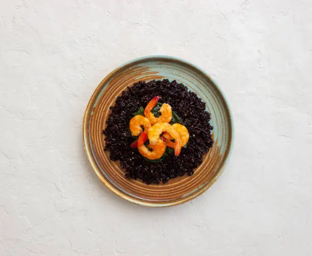 Photo of Black rice risotto with shrimp. Sea food. Diet. Healthy eating.