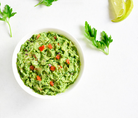 Guacamole dip in bowl over white stone background with free text space. Healthy avocado spread. Top view, flat lay