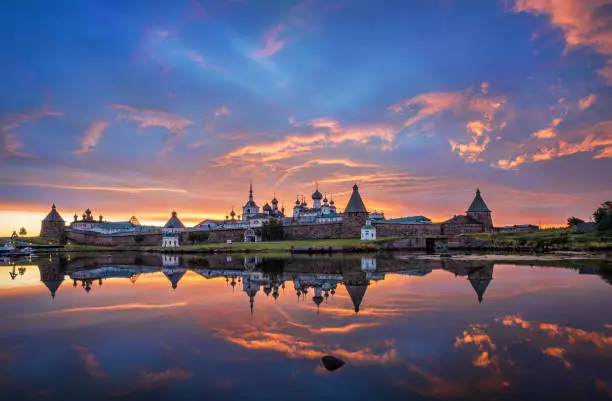 Solovetsky Monastery with a mirror image in the water of the Bay of Prosperity on the Solovetsky Islands under a beautiful dawn pink sky