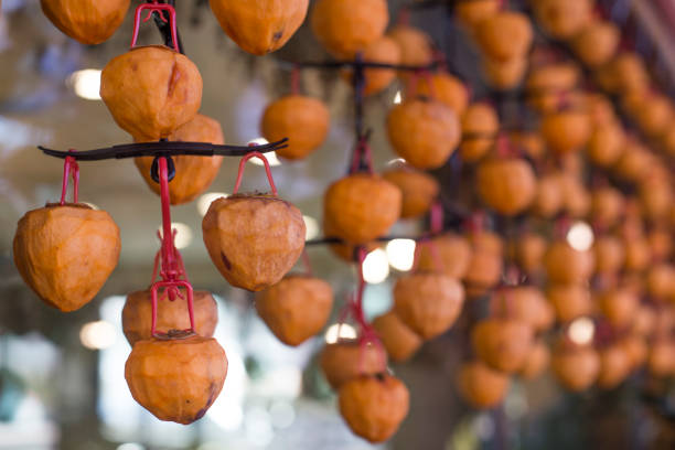 istock Fresh persimmons fruits drying lined up on rope. 1289527919