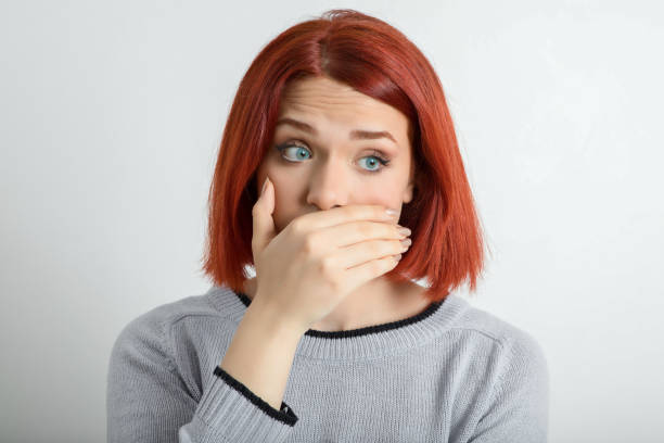 young woman covering her mouth looking at the camera - gasping color image hands covering mouth staring imagens e fotografias de stock