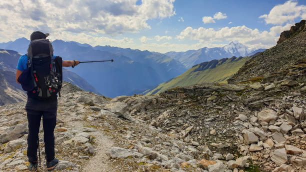 istock A man pointing with hiking stick in direction if Gro?glockner, while hiking in Heiligenblut region in Austria. There are many high chains of Alps behind him. Narrow pathway. Looking for directions 1289531737